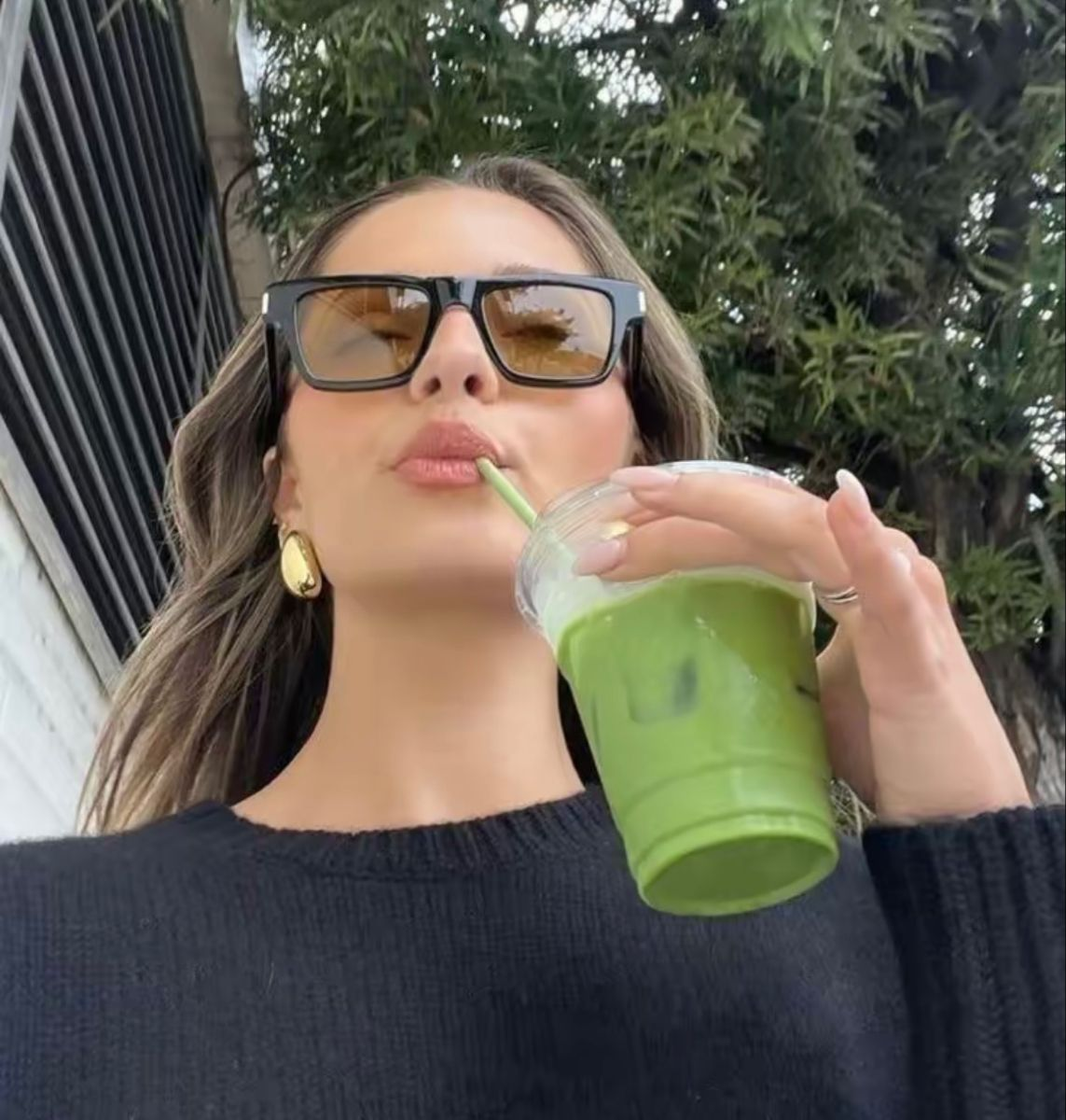 Woman sipping an iced matcha latte outdoors